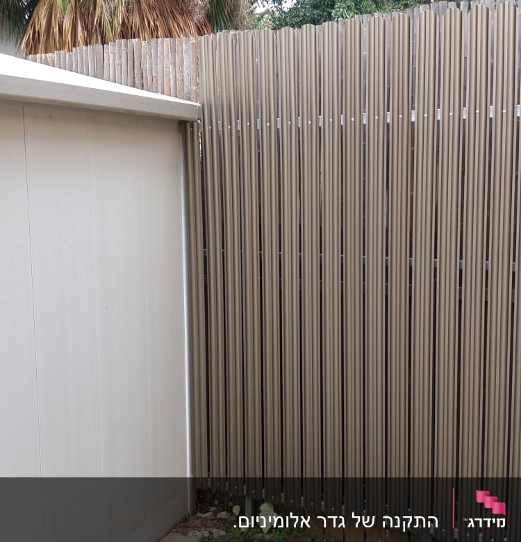 גדר עץ גבוהה ליד קיר מתכת אפור